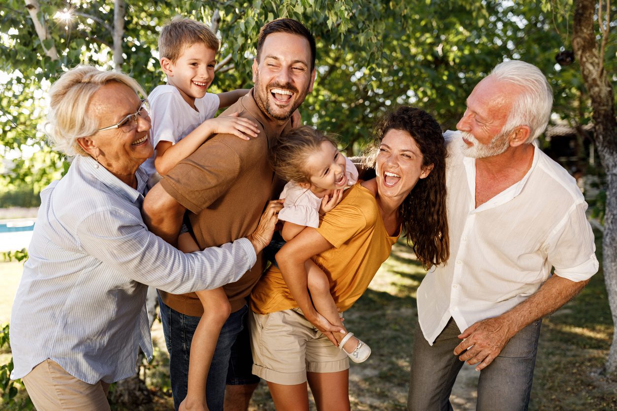 Candid photo of multi-generational family outside with young kids on their parents back representing the importance of using transfer on death (TOD) designations