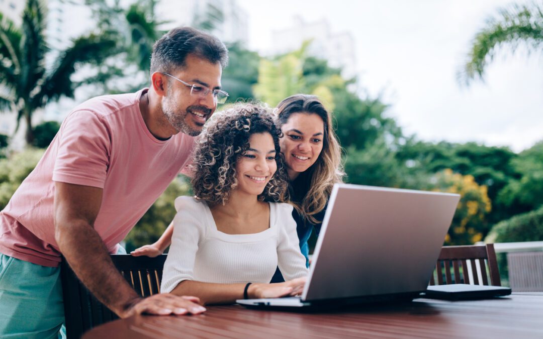 Parents sitting outside with teenage daughter on laptop discussing her custodial Roth IRA