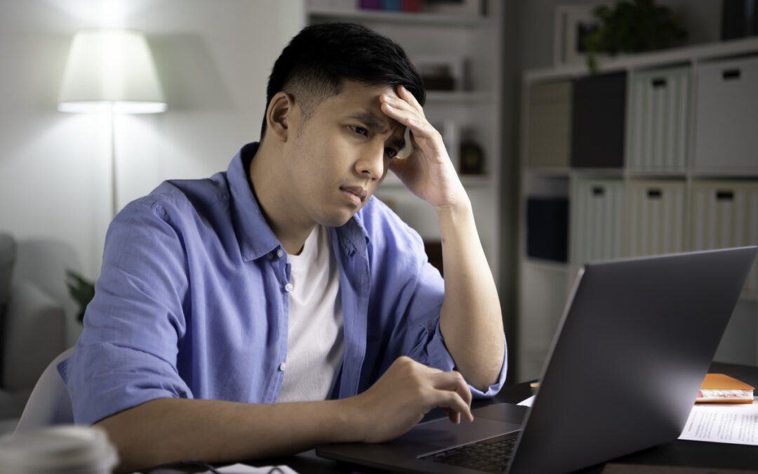 Young adult man looking at laptop with a confused expression as he figures out what to do about an inherited IRA