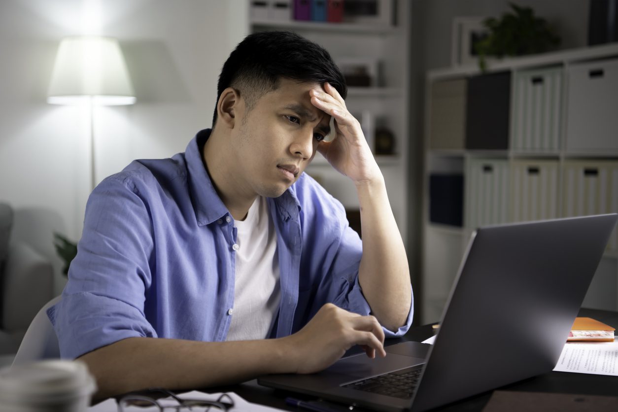 Young adult man looking at laptop with a confused expression as he figures out what to do about an inherited IRA