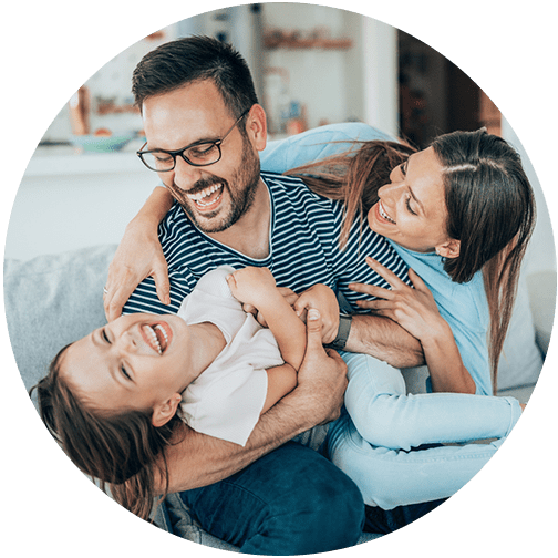 Parents holding on to each other with dad holding daughter in arms and laughing