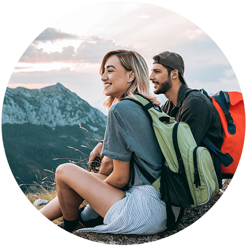 Couple sitting on mountain with backpacks on and contemplating their financial planning needs to continue traveling