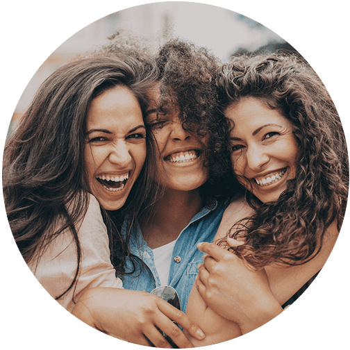 Three female friends hugging and smiling