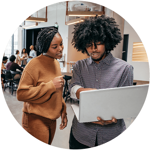 Two young professionals meeting in the office and looking at a laptop