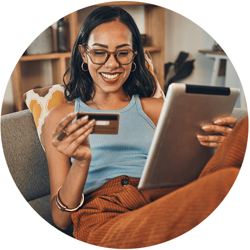 Women looking at credit card and smiling with tablet in hand evaluating her cash flow analysis