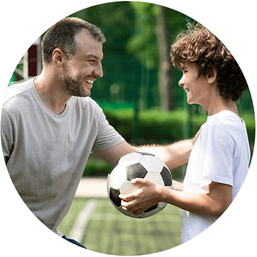 Dad coaching son who is holding soccer ball