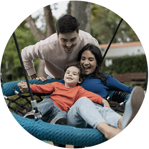 Mom and child swinging on round swing with dad pushing grateful that his family is protected through estate planning