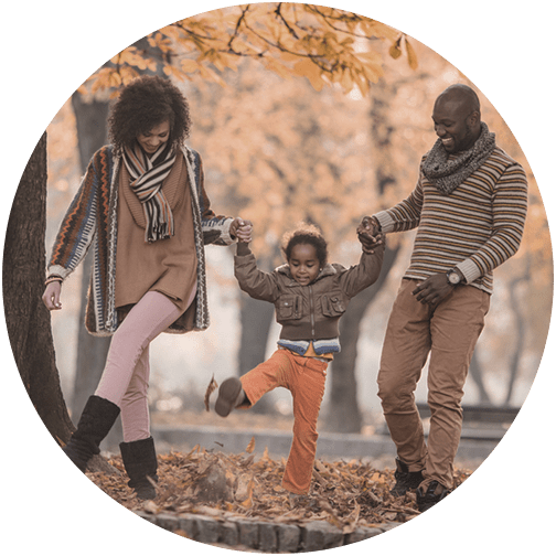 Young family representing planned ahead financial planning clients swinging child in air for fall pictures