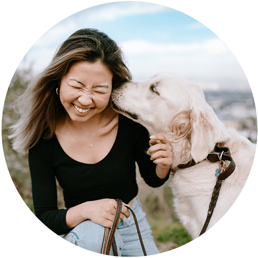 Female smiling as dog kisses her face grateful to have been included in her financial planning