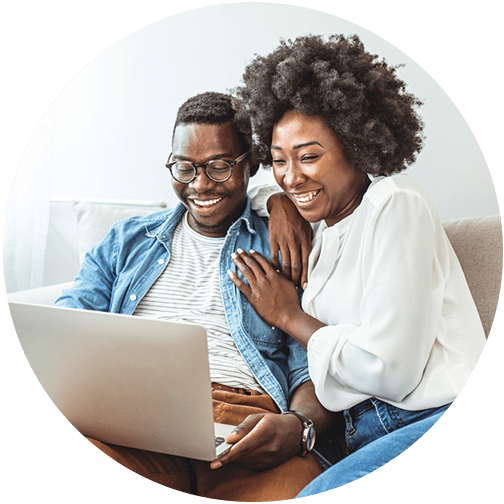 Young couple on couch and looking at laptop while discussing their retirement goals and retirement planning