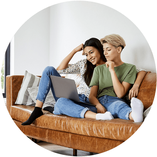 Couple sitting on couch and reviewing their taxes on a laptop