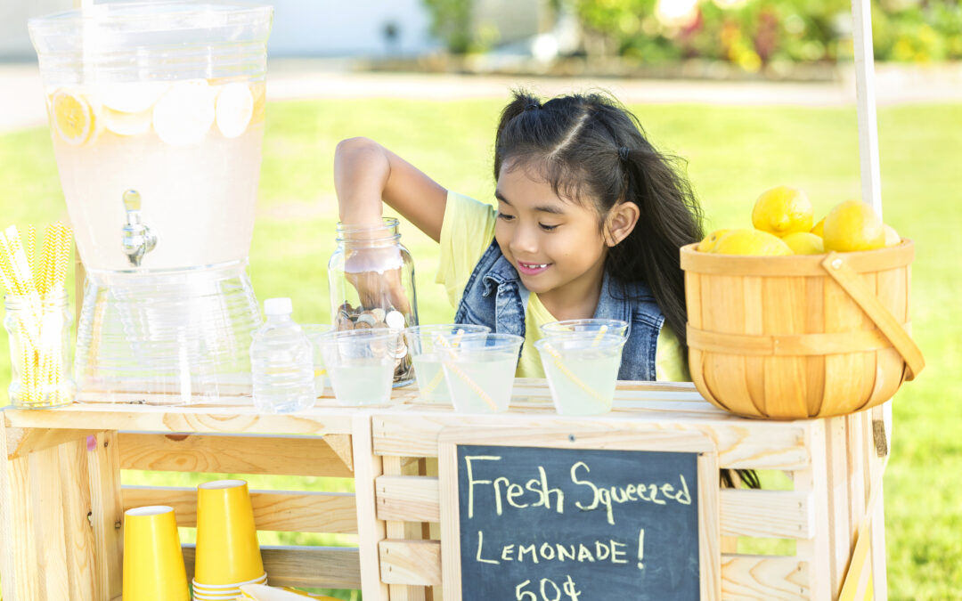 Little girl learning about money with her hand in money jar at her lemonade stand